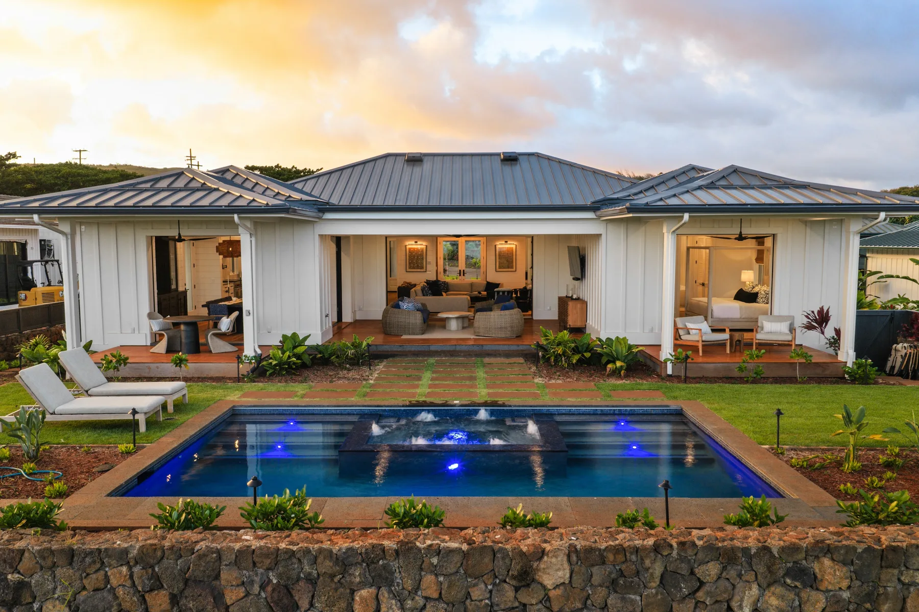 A single-story house opens onto a swimming pool and landscaped patio.