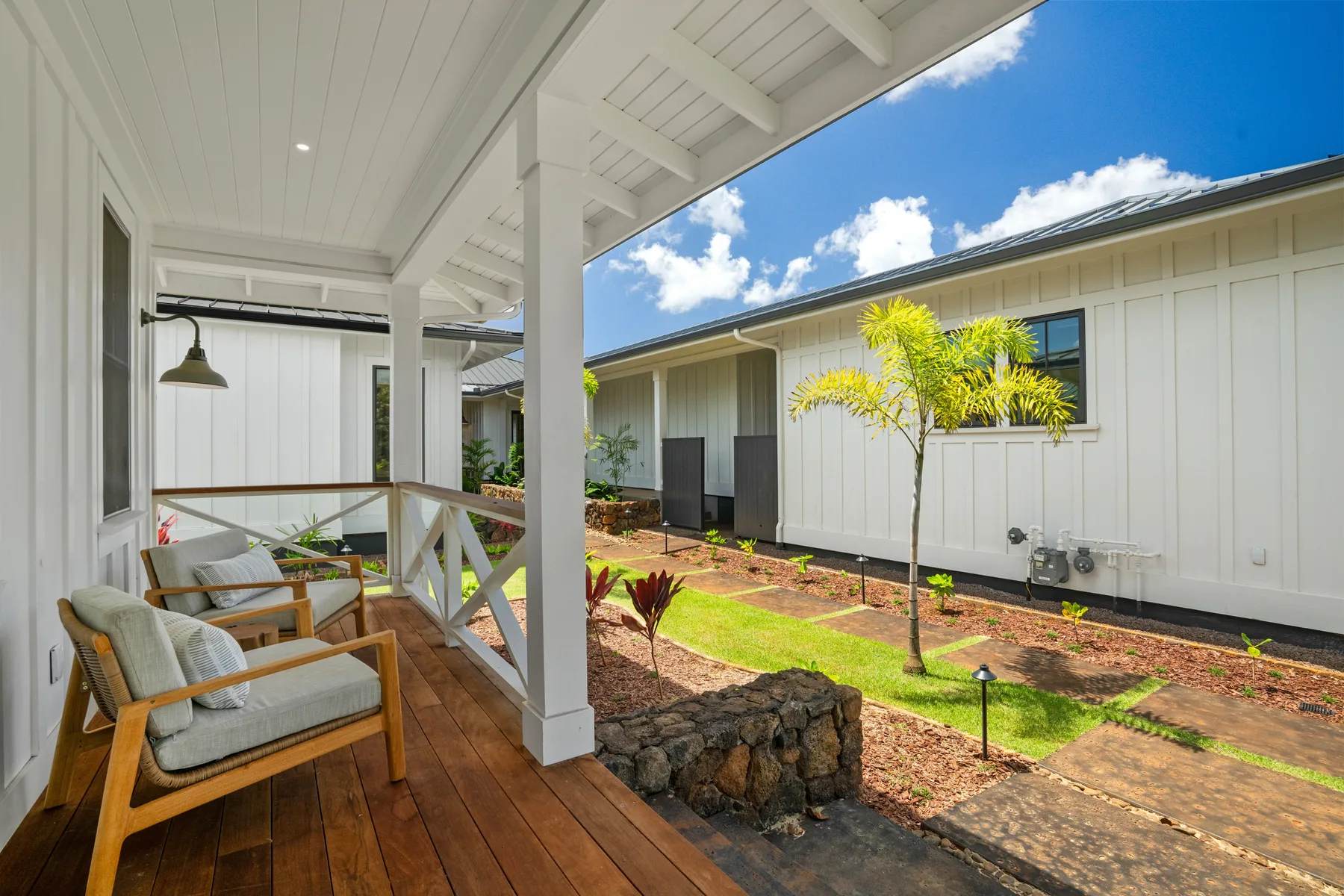 A covered outdoor seating area overlooks a sunny courtyard beside a white building.