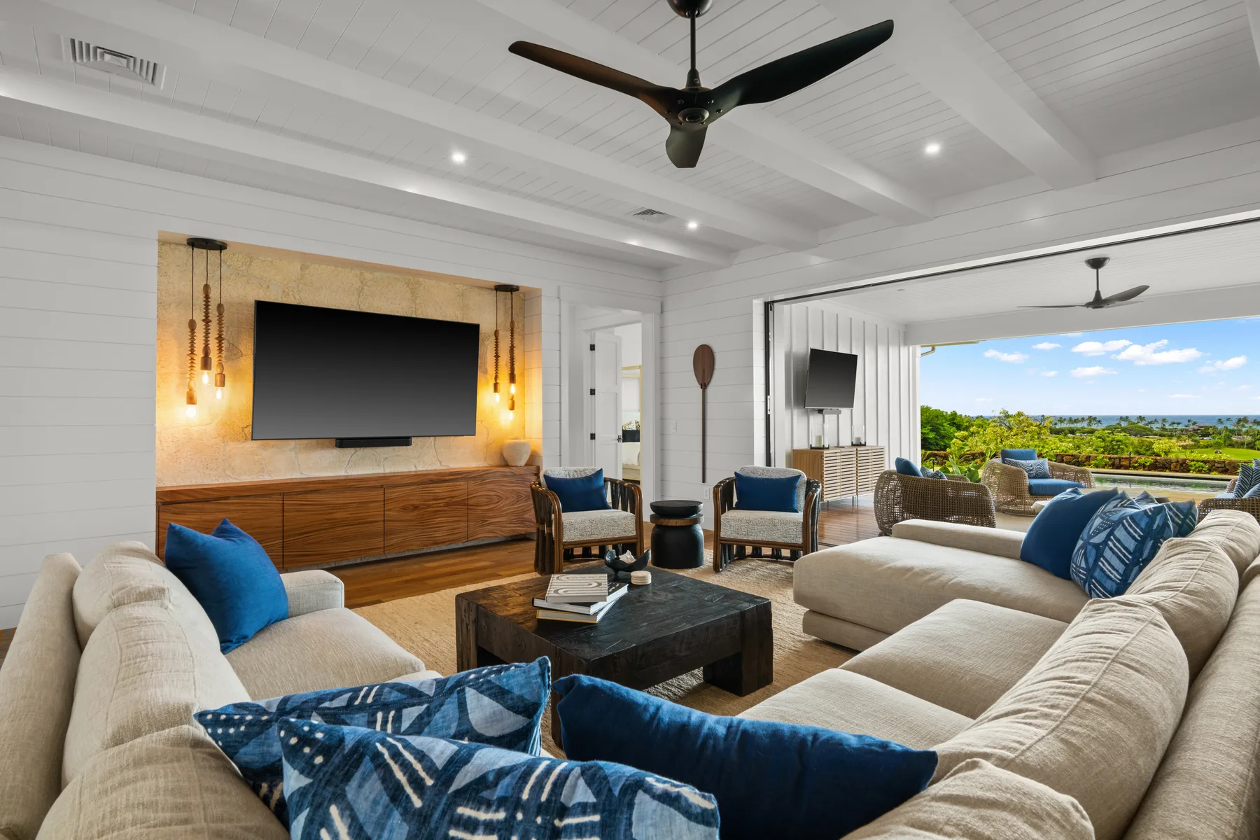 A bright living room with sofas, a television, and a view of the outdoors.