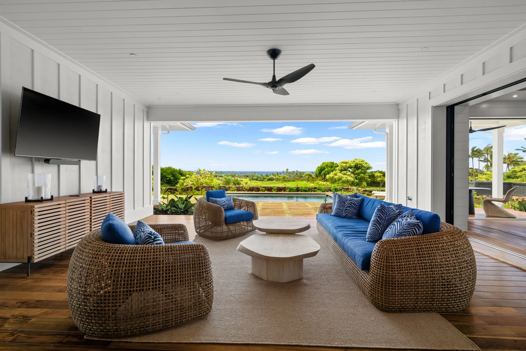 A covered patio seating area opens onto a green landscape.