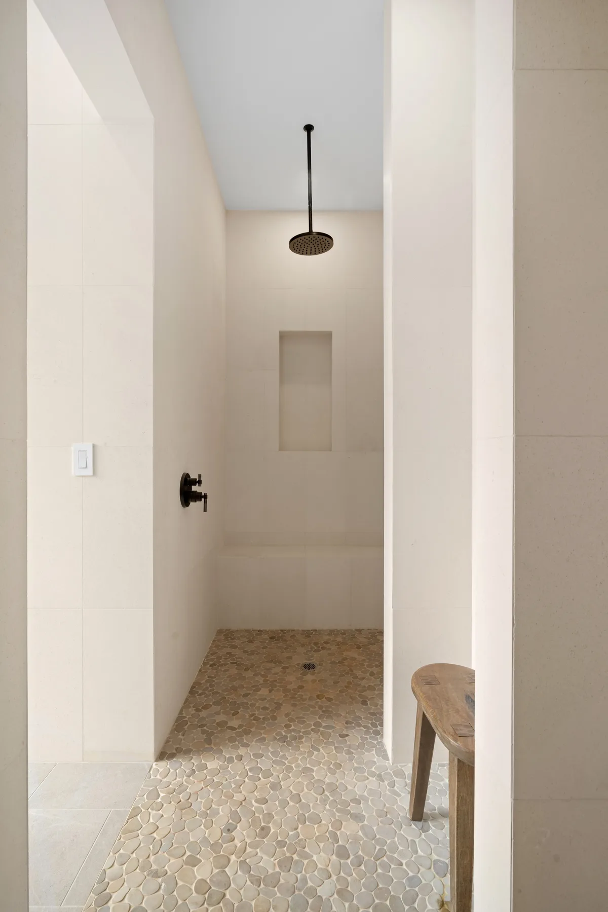 A tiled bathroom shower area with a wall niche and overhead showerhead.