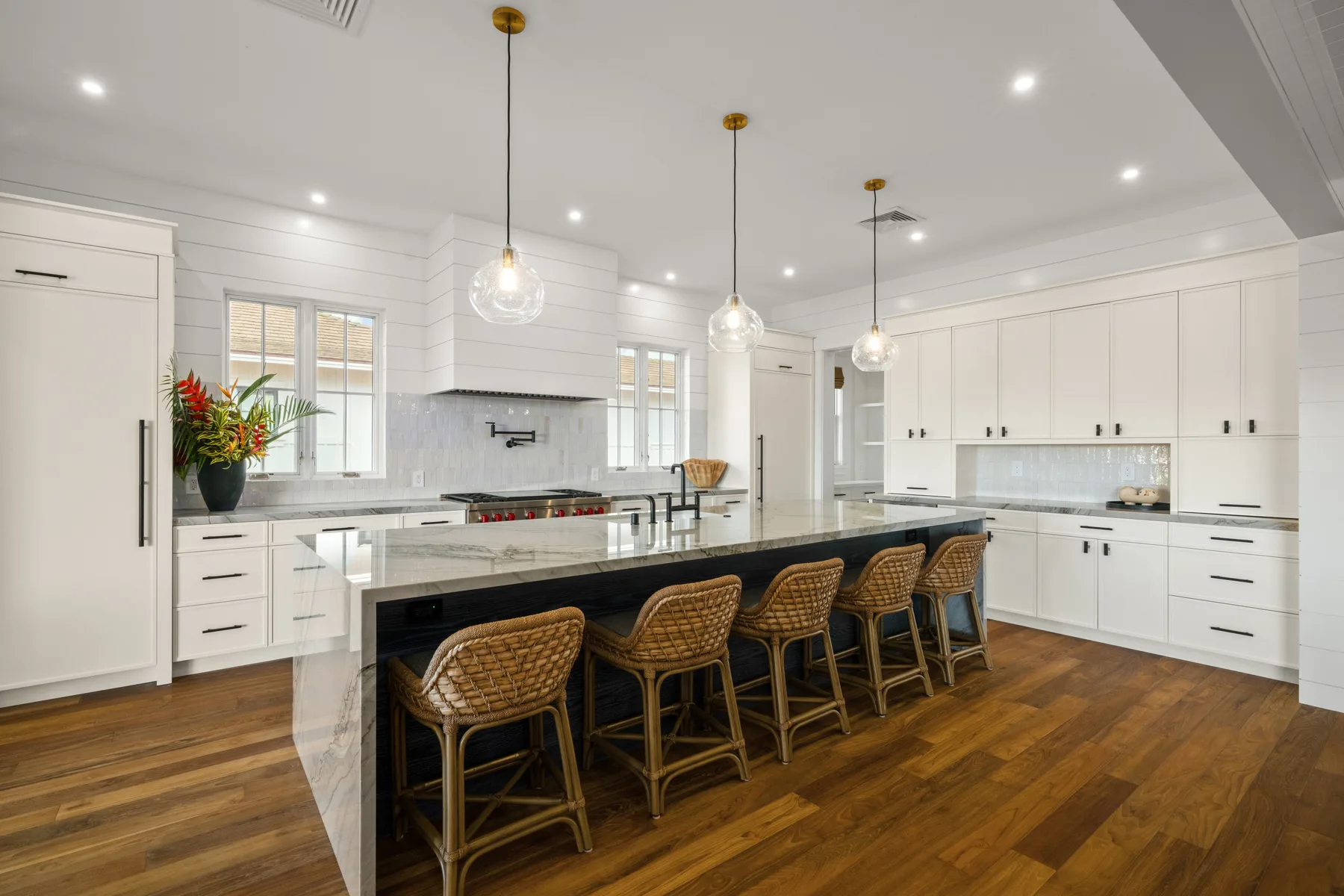 A bright kitchen with a long island, bar seating, and white cabinetry.