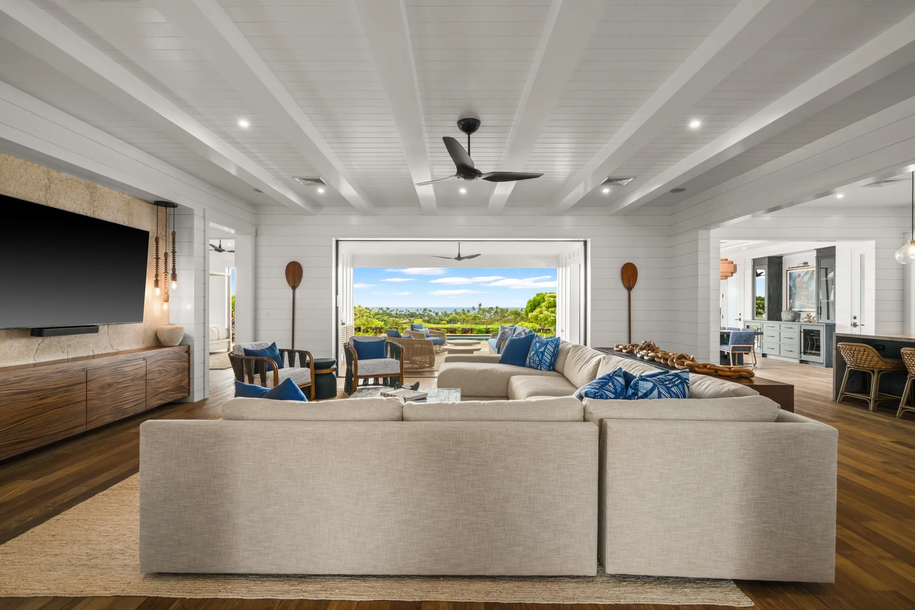 A spacious living room with seating arranged around a television and a view outside.