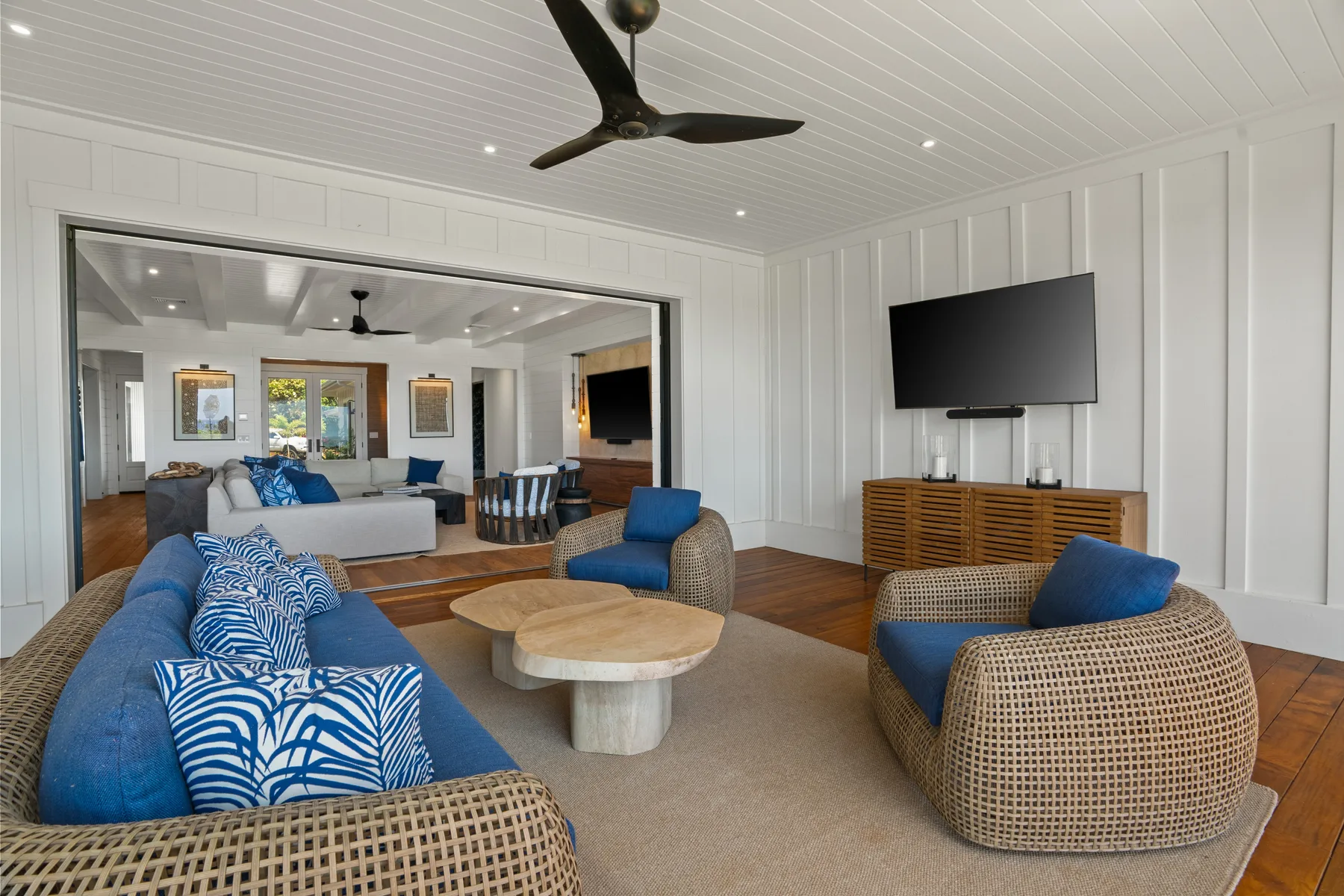 A bright living room with blue seating, a television, and a round coffee table.