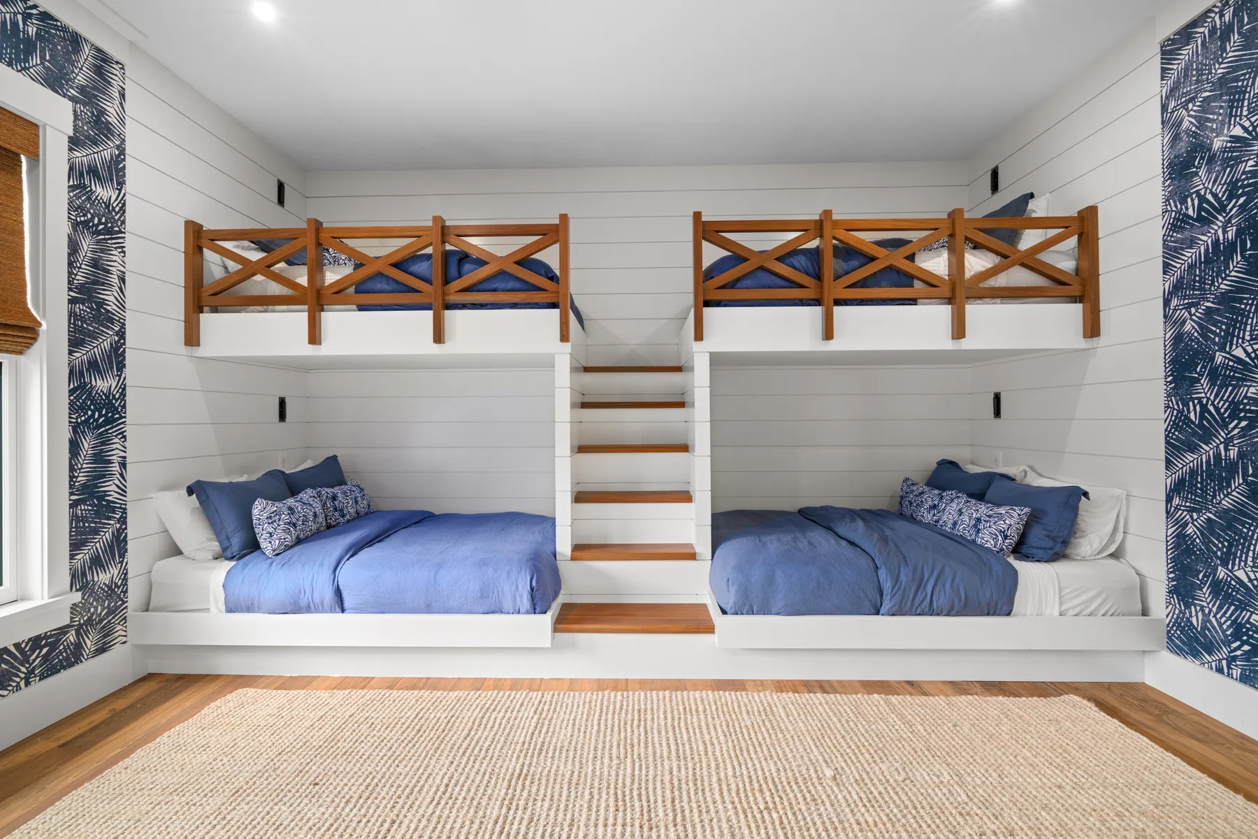 A bright bedroom with two beds beneath raised wooden sleeping platforms.