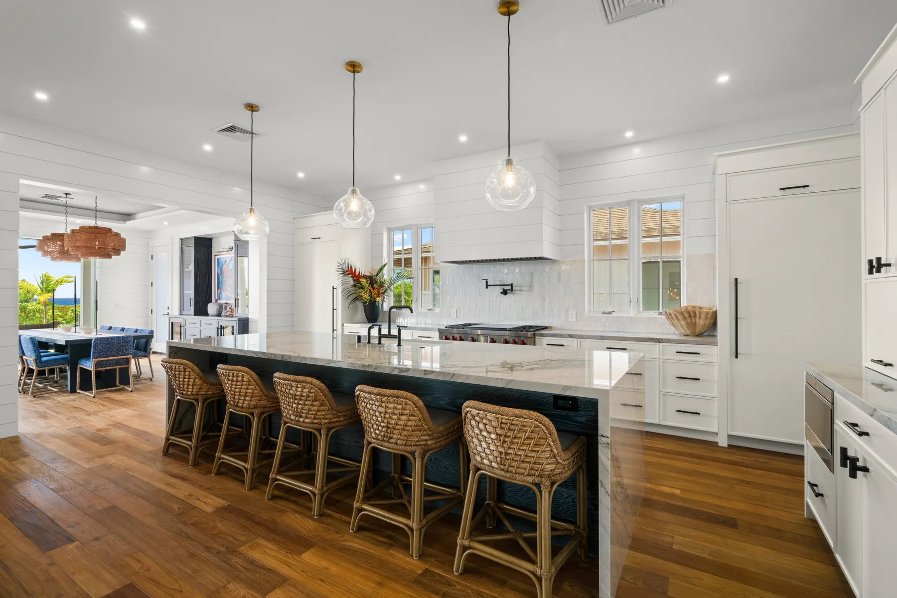 A bright kitchen with a long island, bar seating, and pendant lights.
