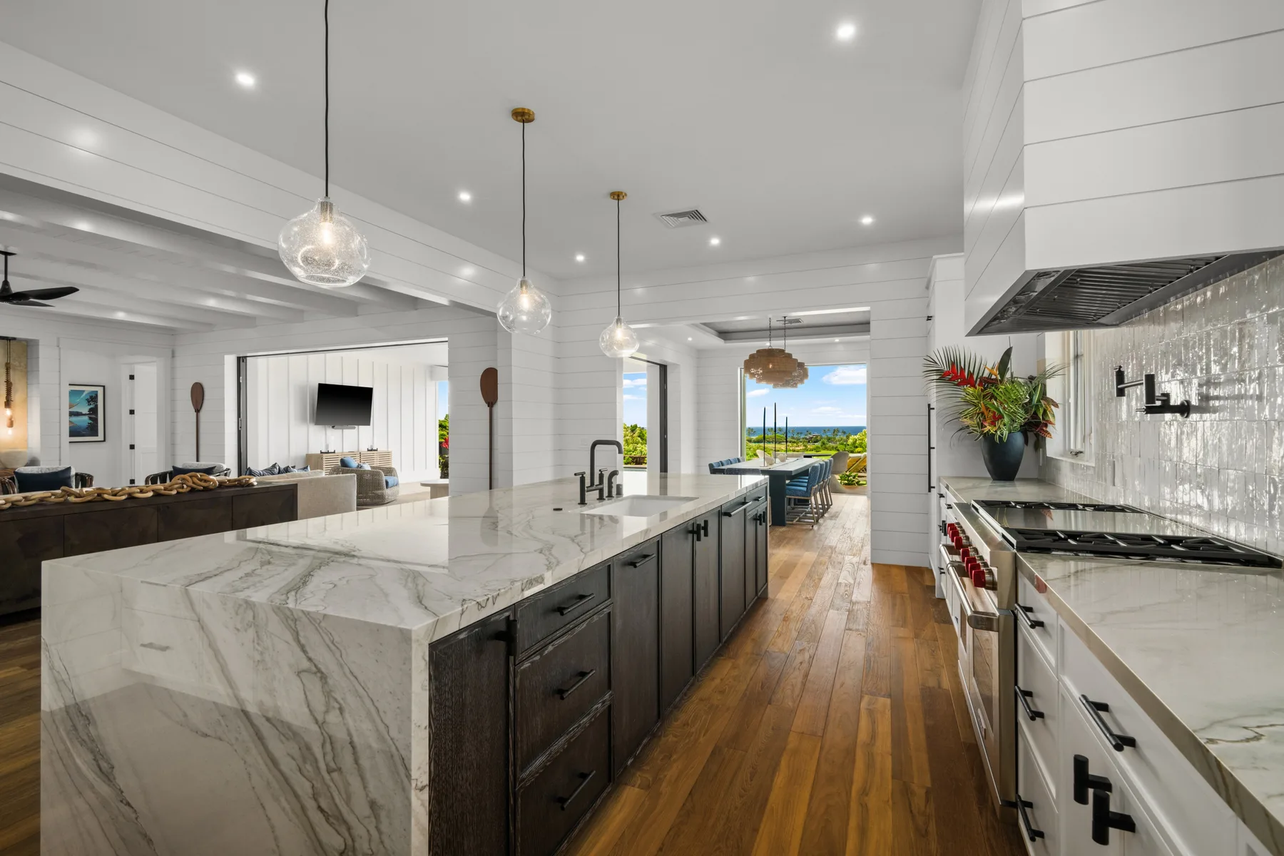 A bright kitchen features a large island and a view through the windows.