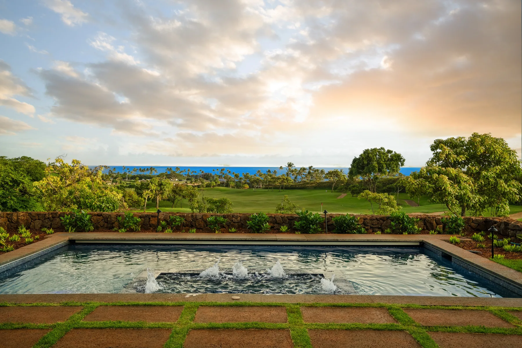 A rectangular fountain pool overlooks a green garden and the sea.