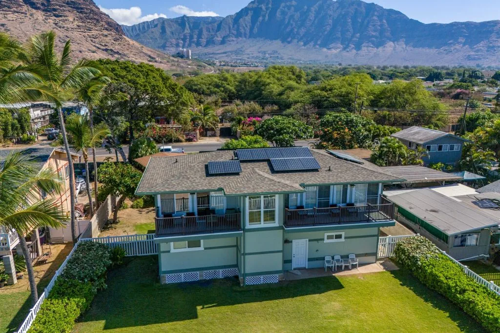 Vista aérea de un edificio residencial bajo con paneles solares y vegetación alrededor.