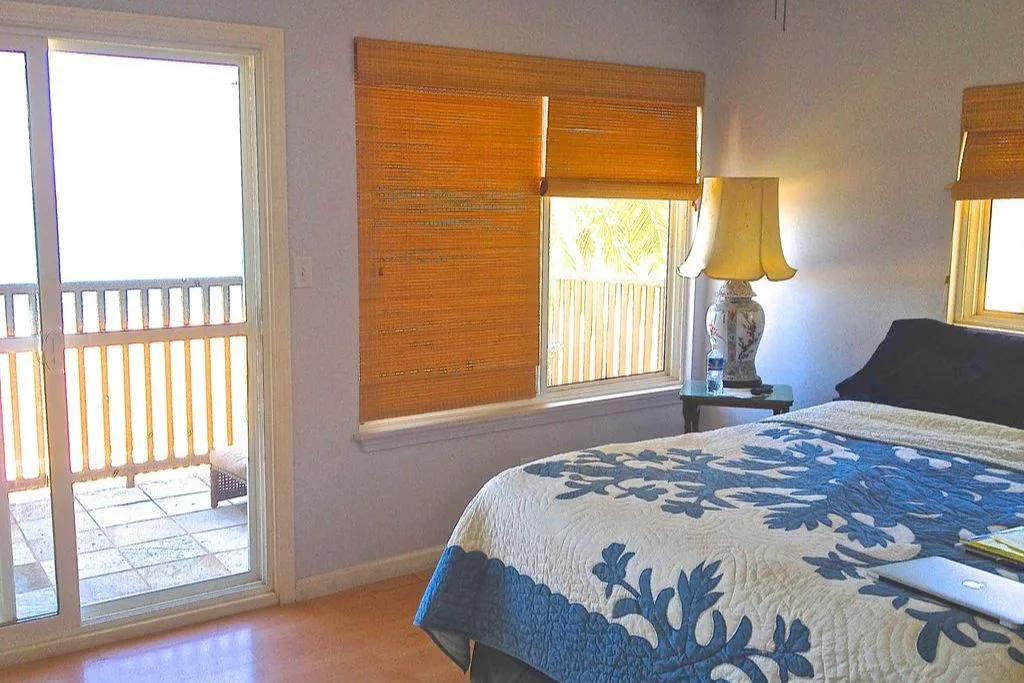 Un dormitorio con una cama cubierta por una colcha floral azul junto a una ventana.