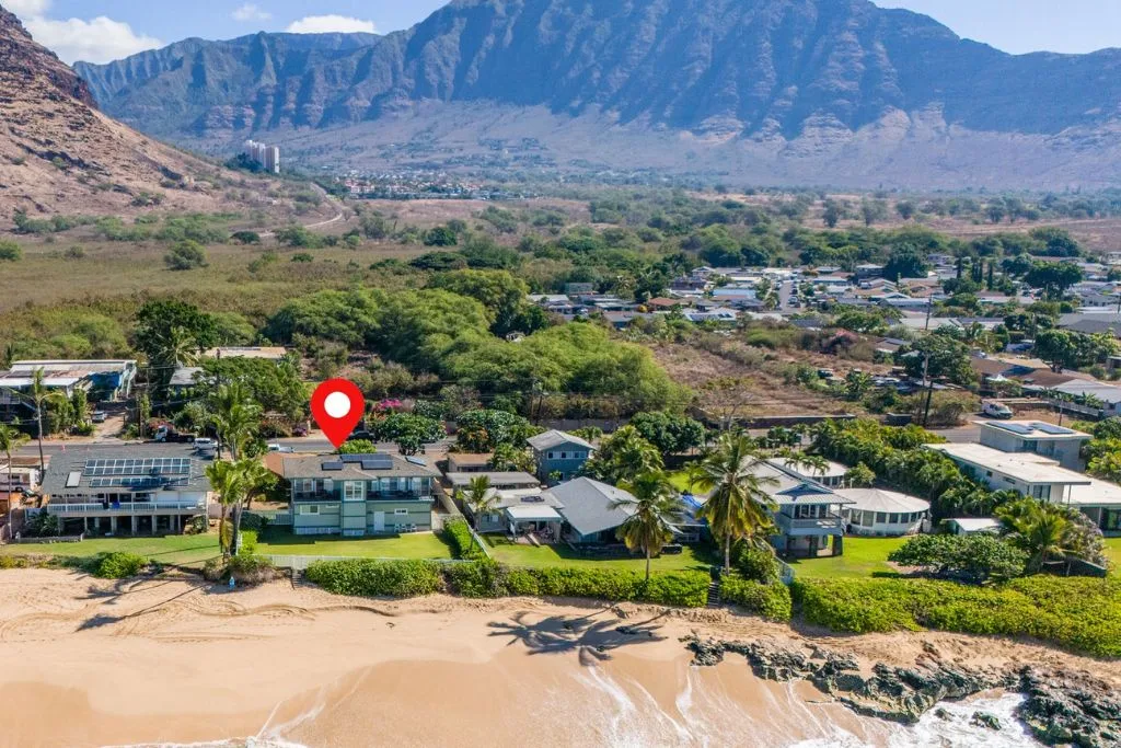 Vista aérea de casas junto a la playa con una cordillera al fondo.