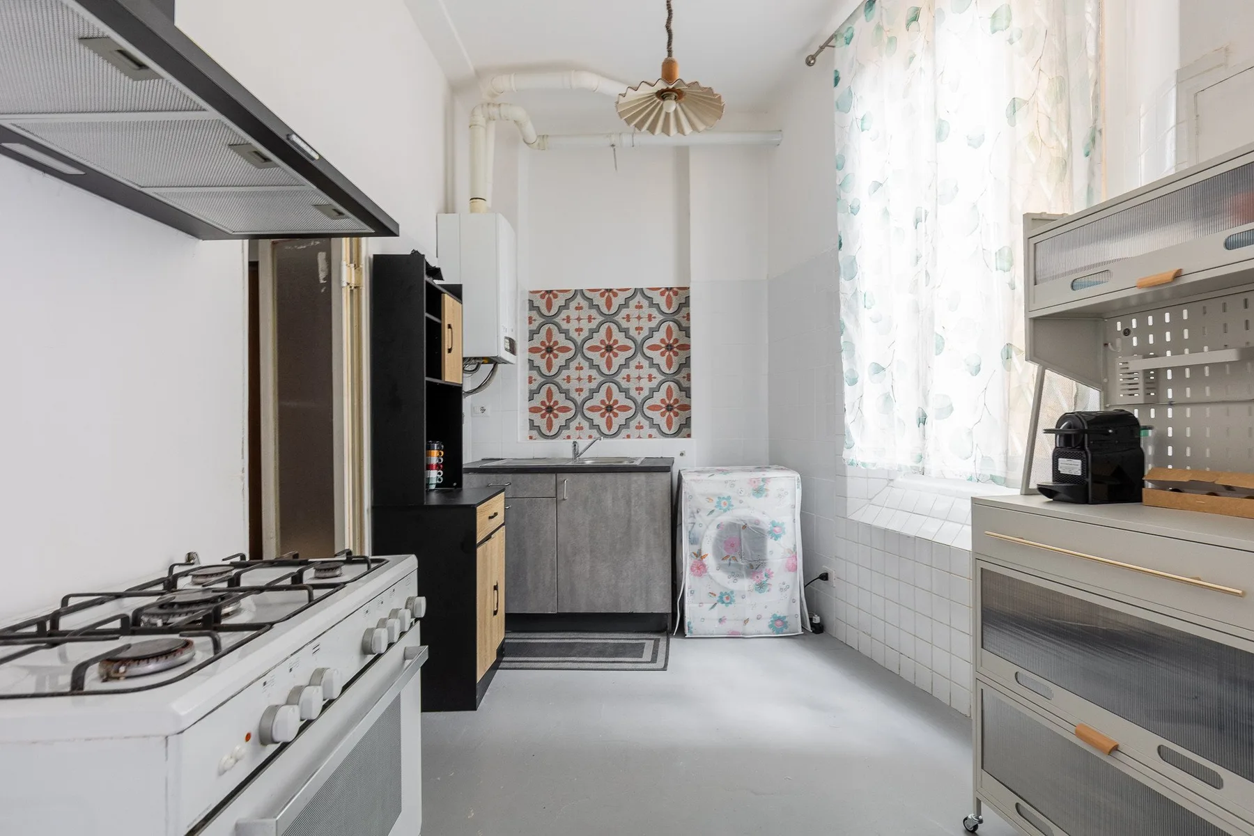 Una cocina luminosa con una estufa de gas, gabinetes y un salpicadero estampado.