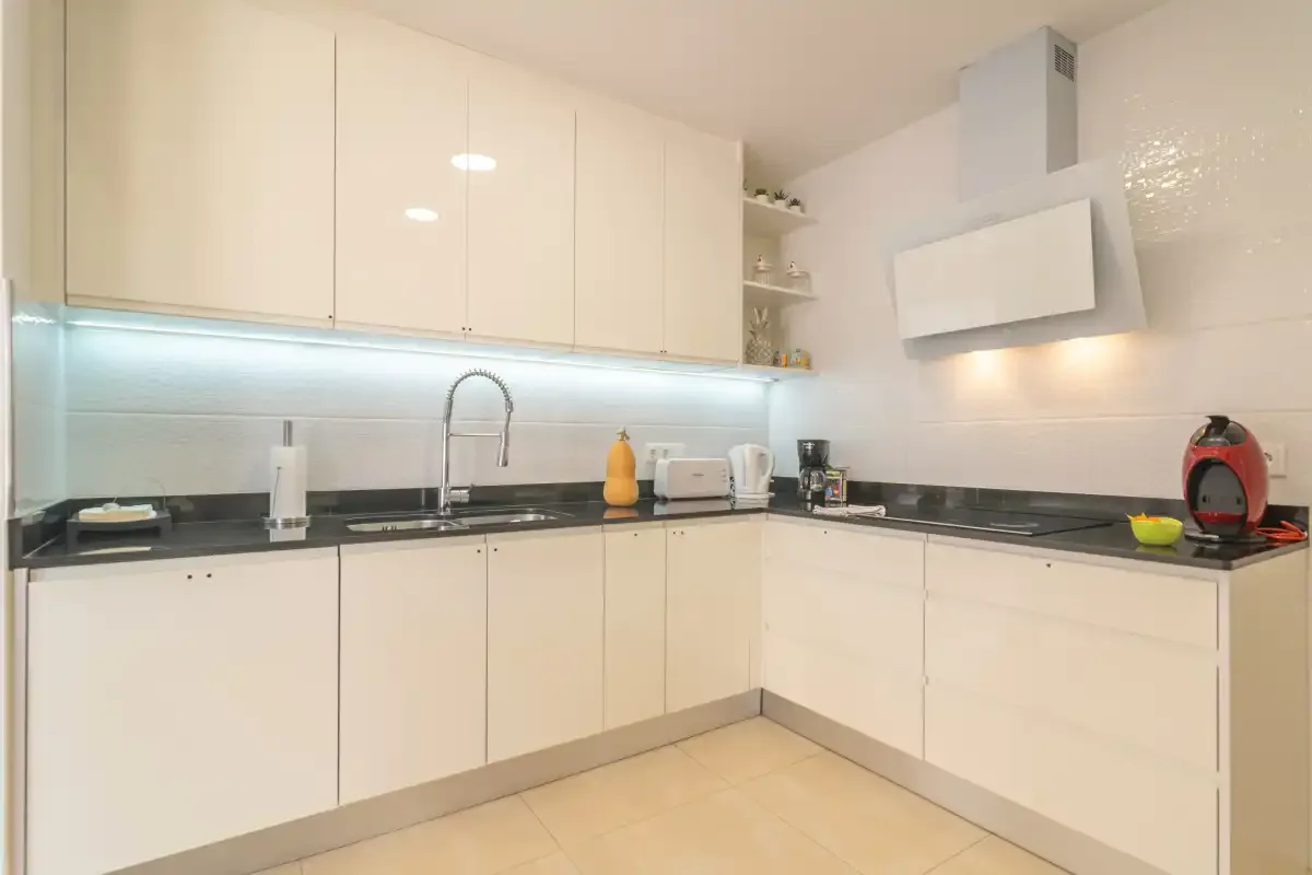 A bright modern kitchen with white cabinets and a dark countertop.