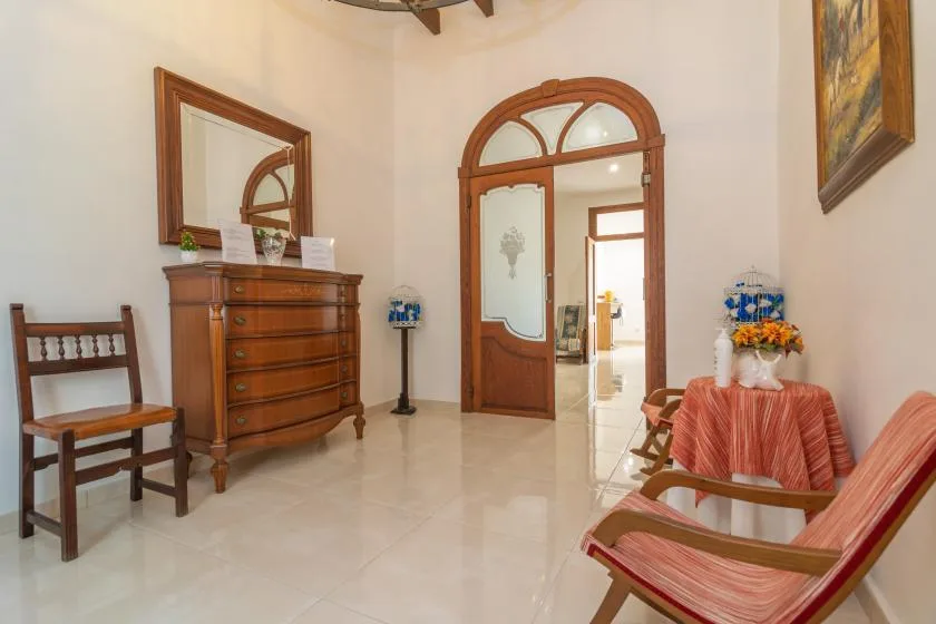 A furnished sitting room with wooden seating, a dresser, and an arched doorway.