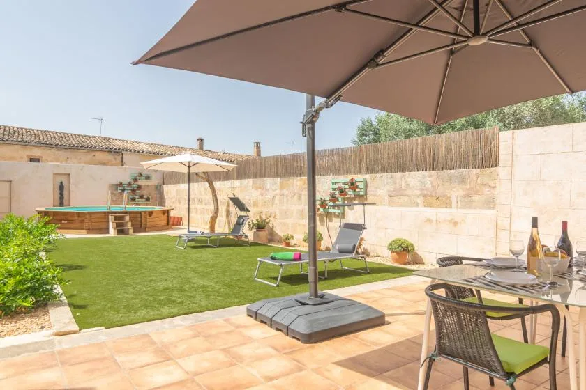 A sunny patio overlooks a small lawn with outdoor seating and umbrellas.