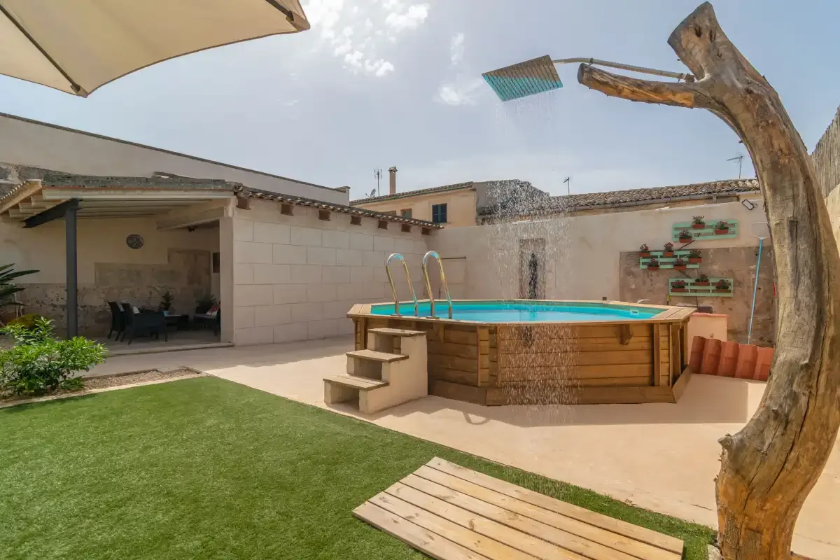 A courtyard pool sits beside a lawn and shaded seating area.