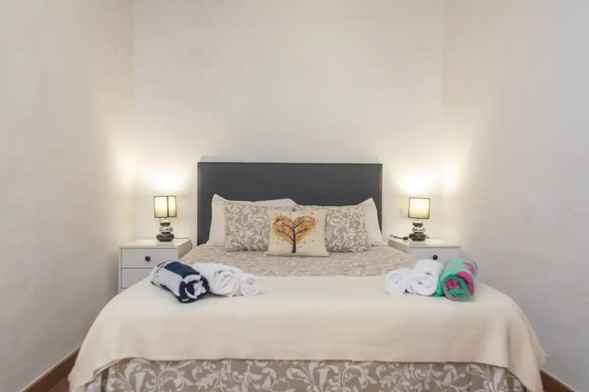 A bedroom with a neatly made bed and matching bedside lamps.