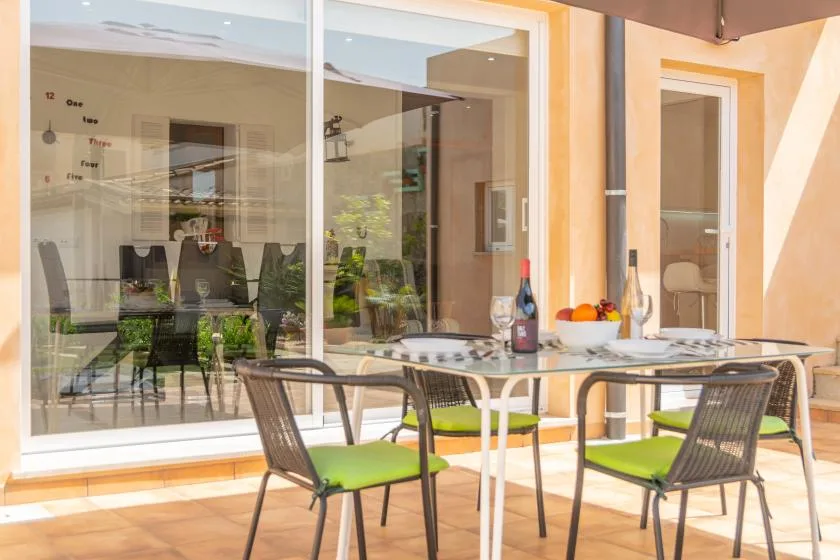 An outdoor dining area with a table and chairs beside glass doors.
