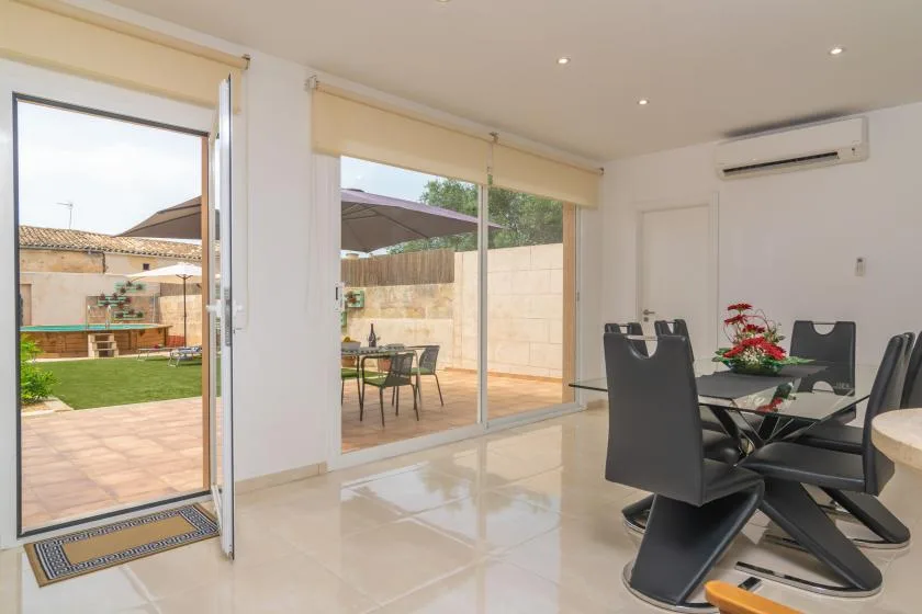 A bright dining area opens through large glass doors to a furnished patio and garden.