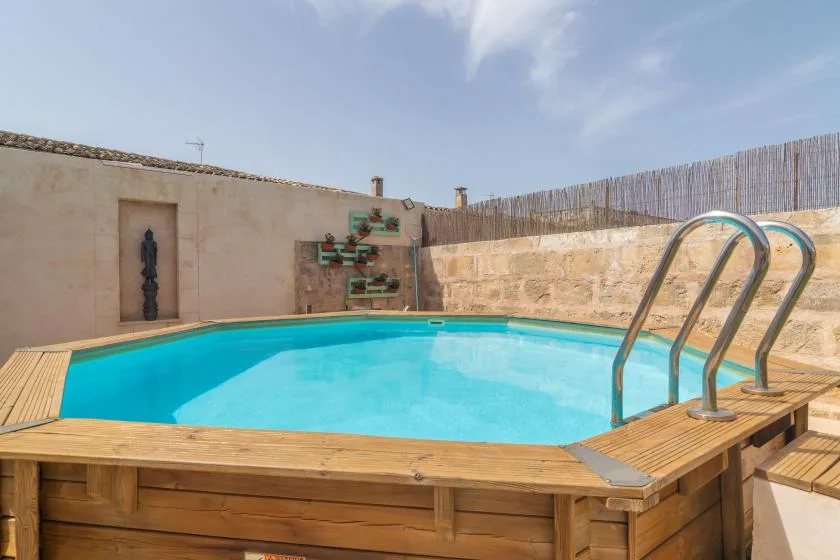 An outdoor swimming pool with a wooden deck and metal ladder.