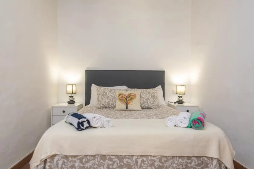 A bedroom with a neatly made bed and matching bedside lamps.