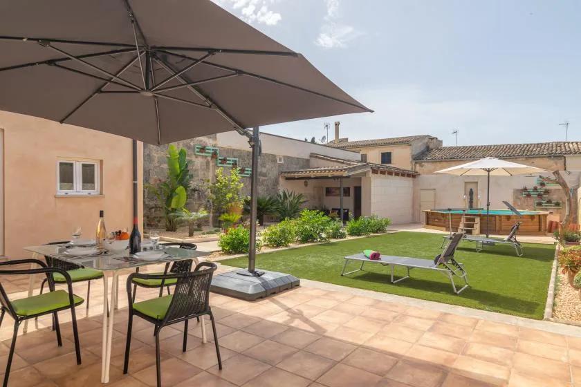 A sunny outdoor patio with a dining table, seating, and a lawn area.