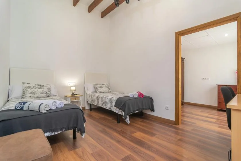 A bedroom with two beds and exposed wooden ceiling beams.