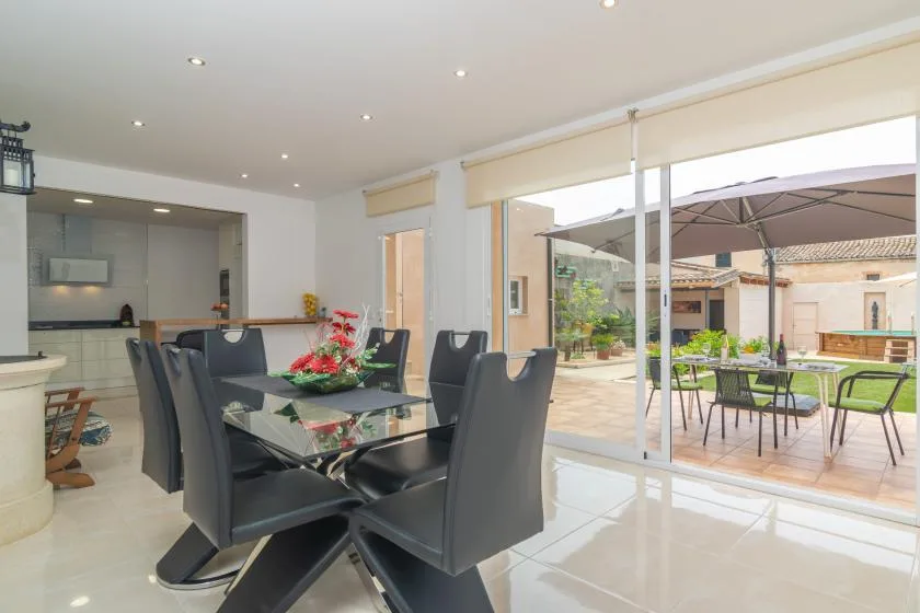 A dining area opens onto a patio with outdoor seating and an umbrella.