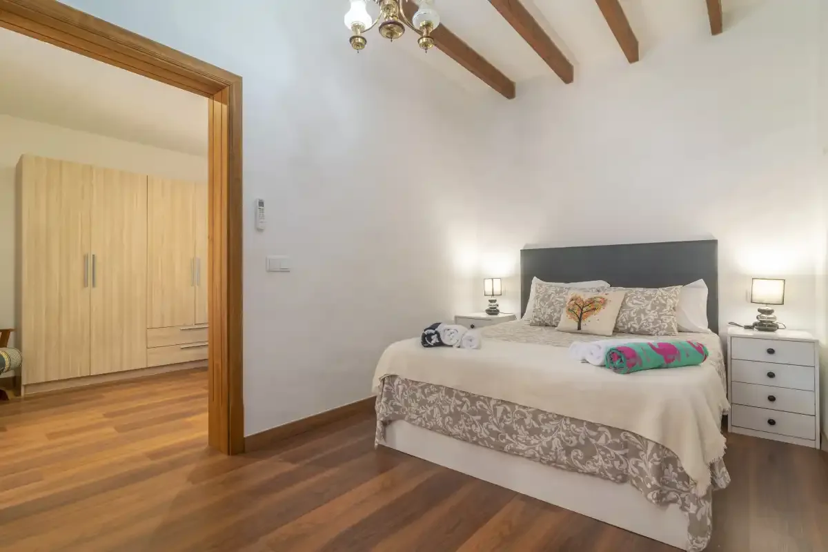 A bedroom with a large bed, bedside tables, and exposed ceiling beams.