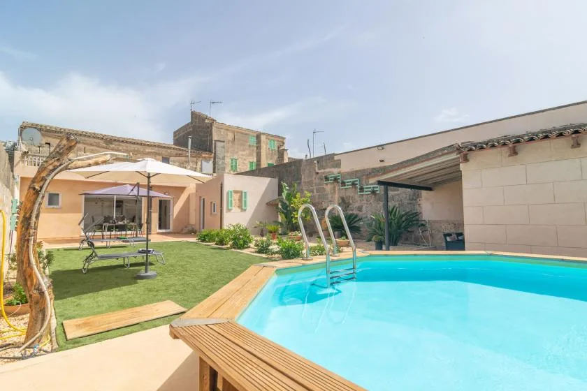 A swimming pool beside a grassy courtyard and low buildings.