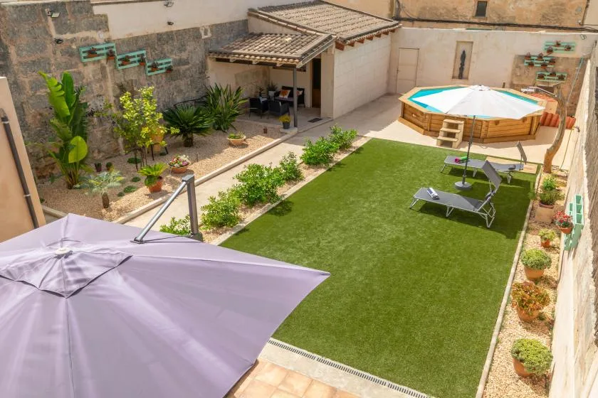 A landscaped courtyard with a raised pool, artificial grass, and lounge seating.