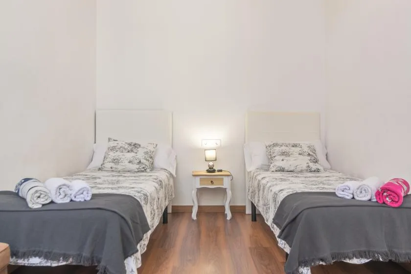 A bright bedroom with two single beds and a small bedside table between them.