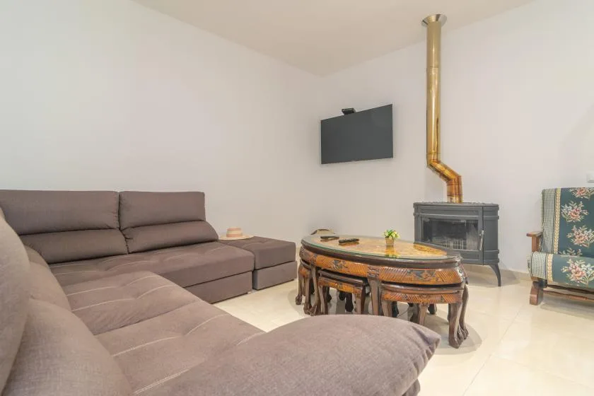 A living room with sectional seating, a coffee table, and a wood stove.
