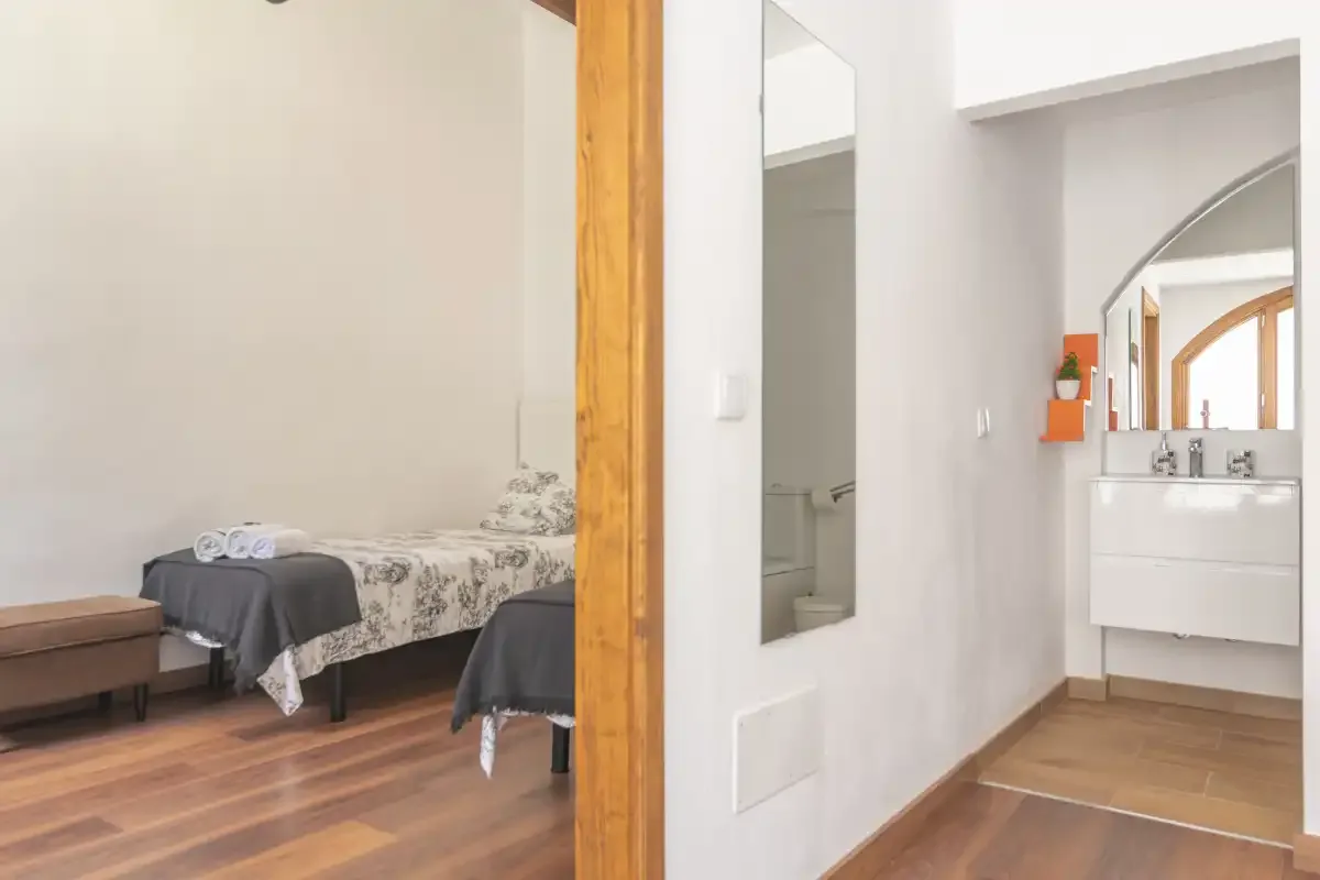 A bedroom with beds and a vanity area visible through the doorway.