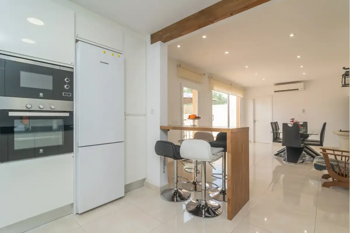 An open-plan kitchen and dining area with a breakfast counter and table.