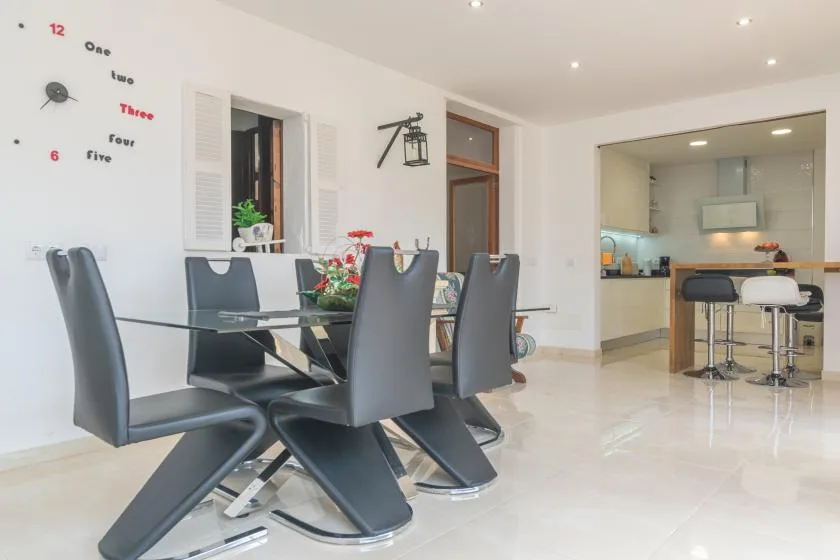 A dining area with dark seating and a table beside an open kitchen.