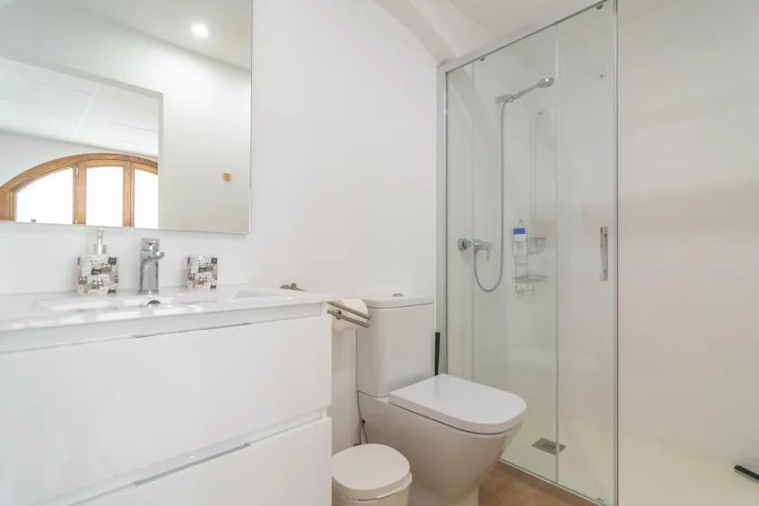 A bright bathroom with a sink, toilet, and glass shower.