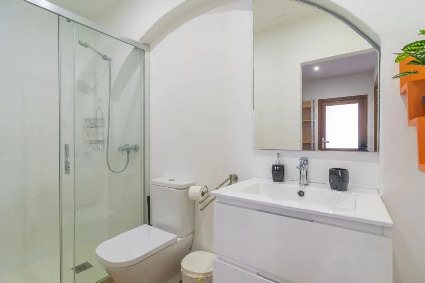 A bright bathroom with a glass shower and a sink beneath a large mirror.