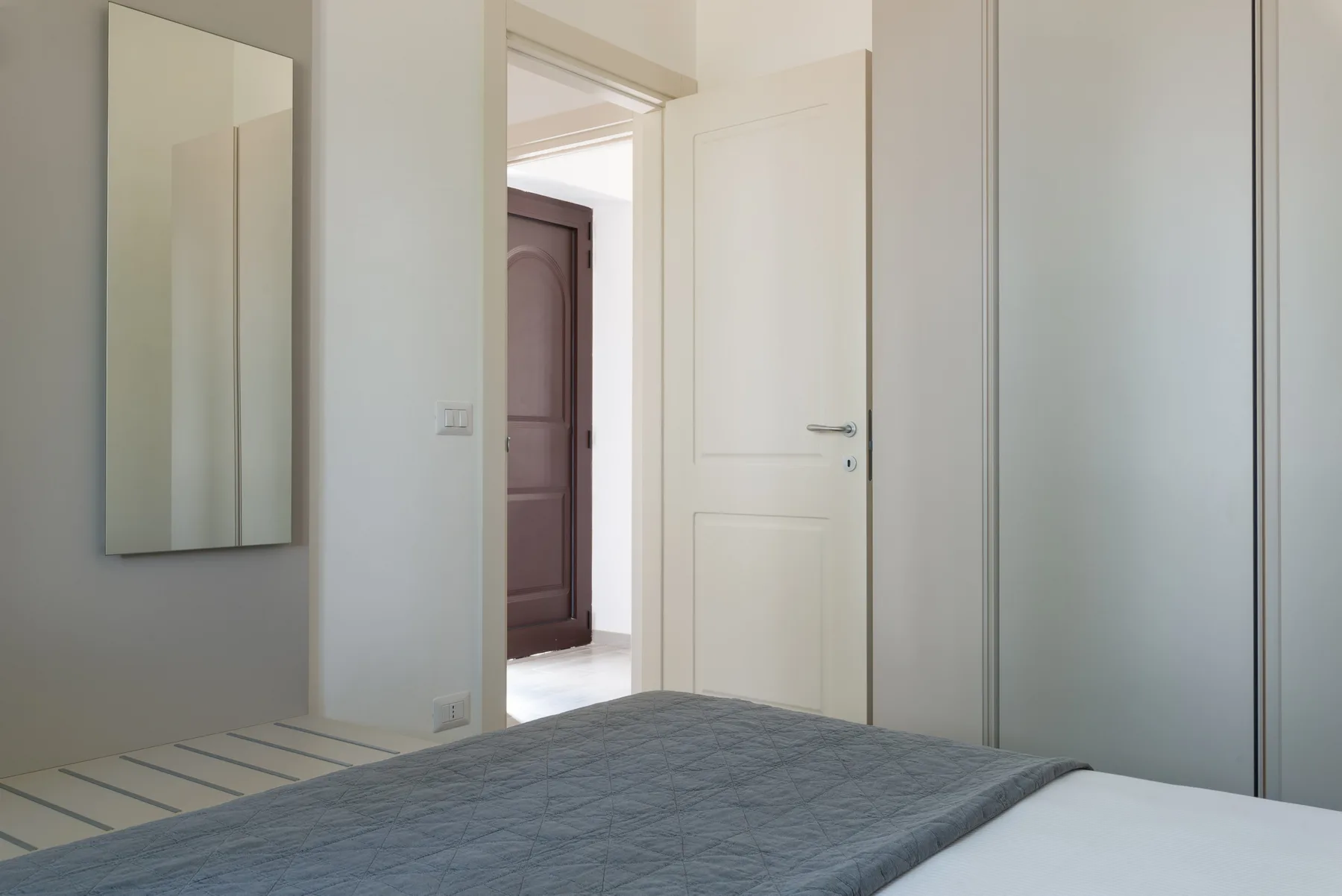 Un dormitorio con una cama junto a una puerta abierta que da a un pasillo.