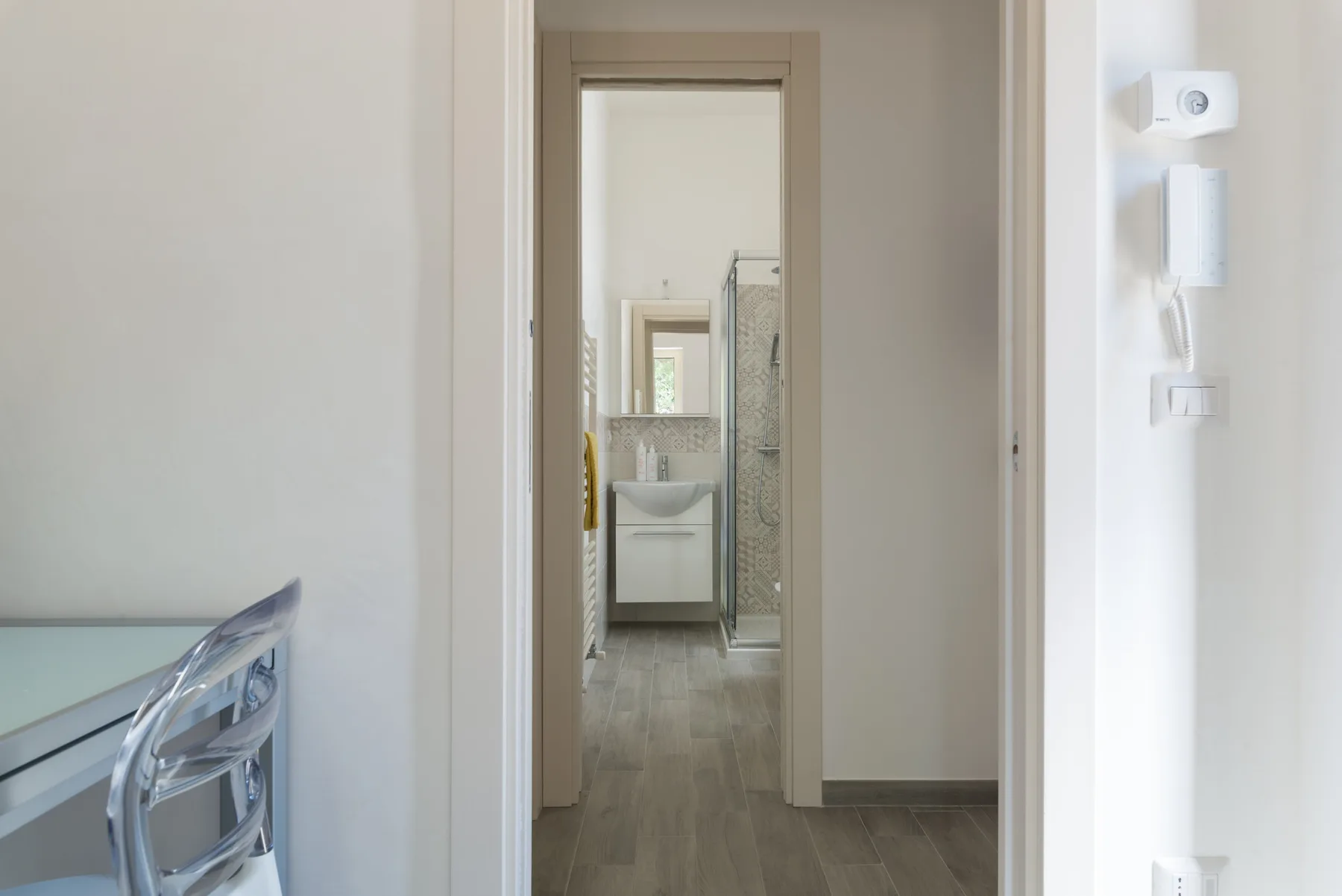Un pasillo conduce a un baño con lavabo y ducha.