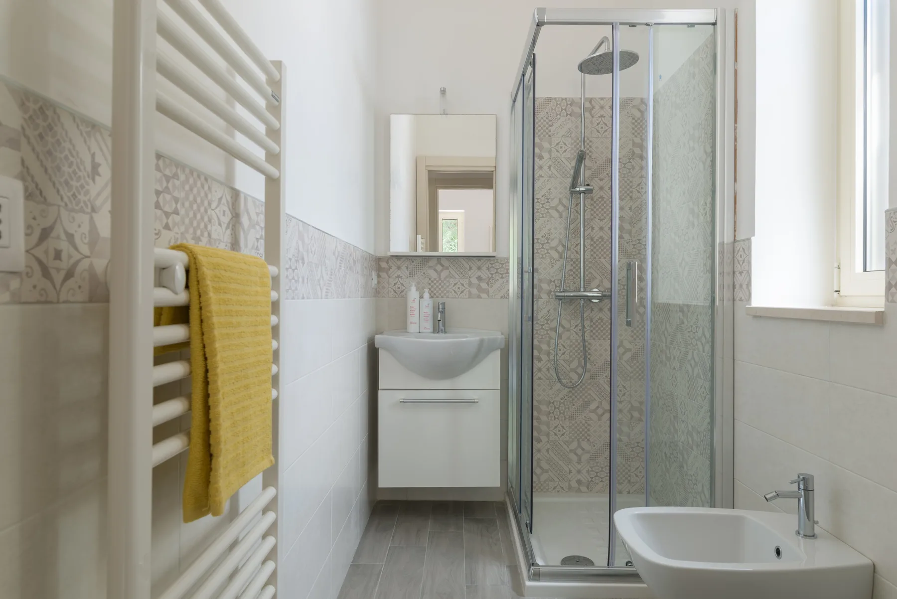 Un baño luminoso con ducha de vidrio, lavabo y bañera.