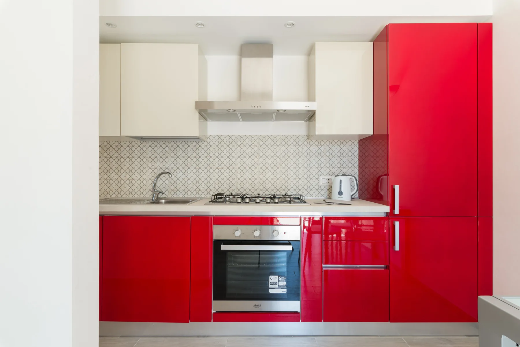 Una cocina moderna con gabinetes rojos, una placa de cocción y un horno.