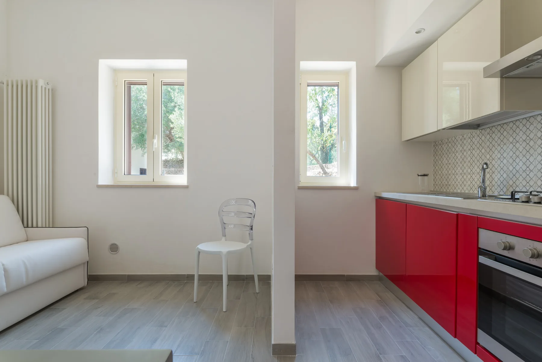 Un interior luminoso combina una sencilla zona de estar con una cocina roja y blanca.
