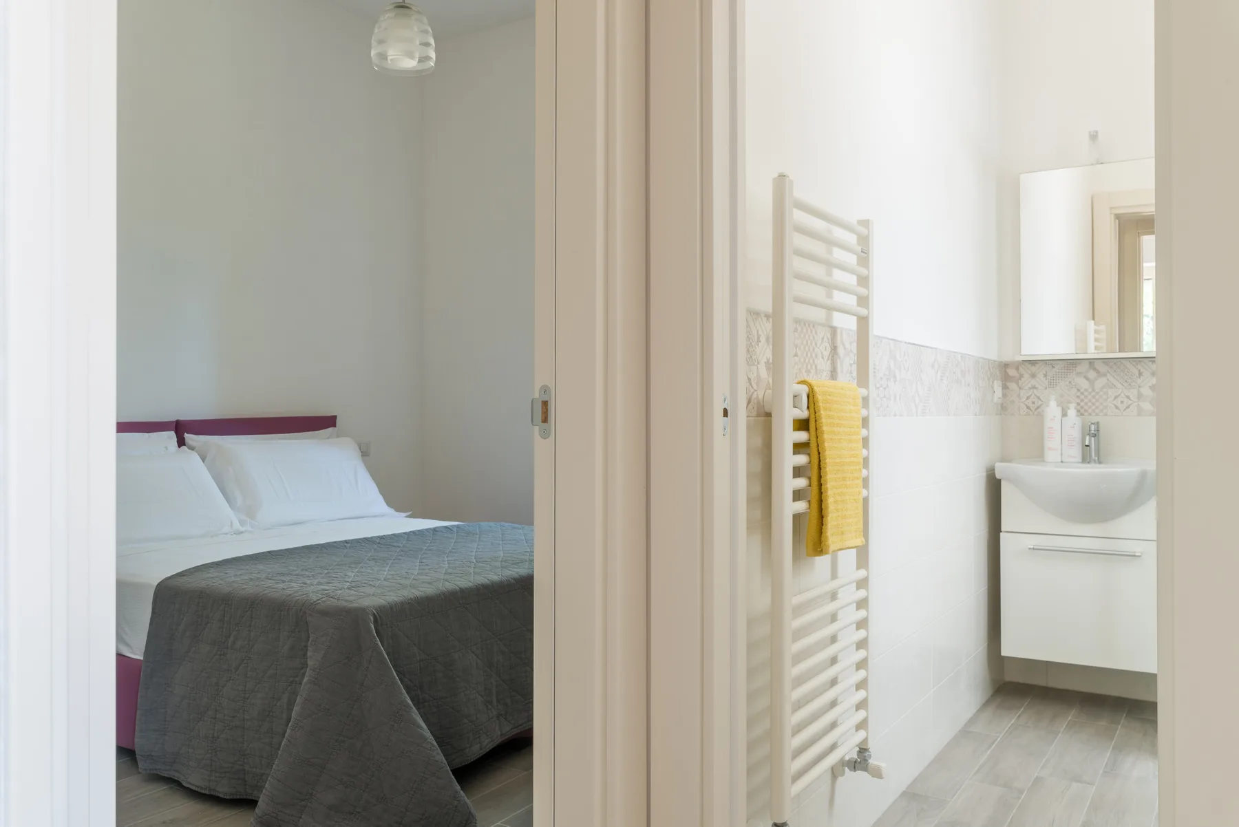 Un dormitorio y un baño contiguo, con una cama y un lavabo de pared.