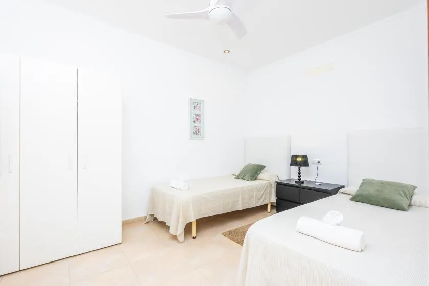 Un dormitorio luminoso con dos camas individuales y una mesita de noche entre ellas.
