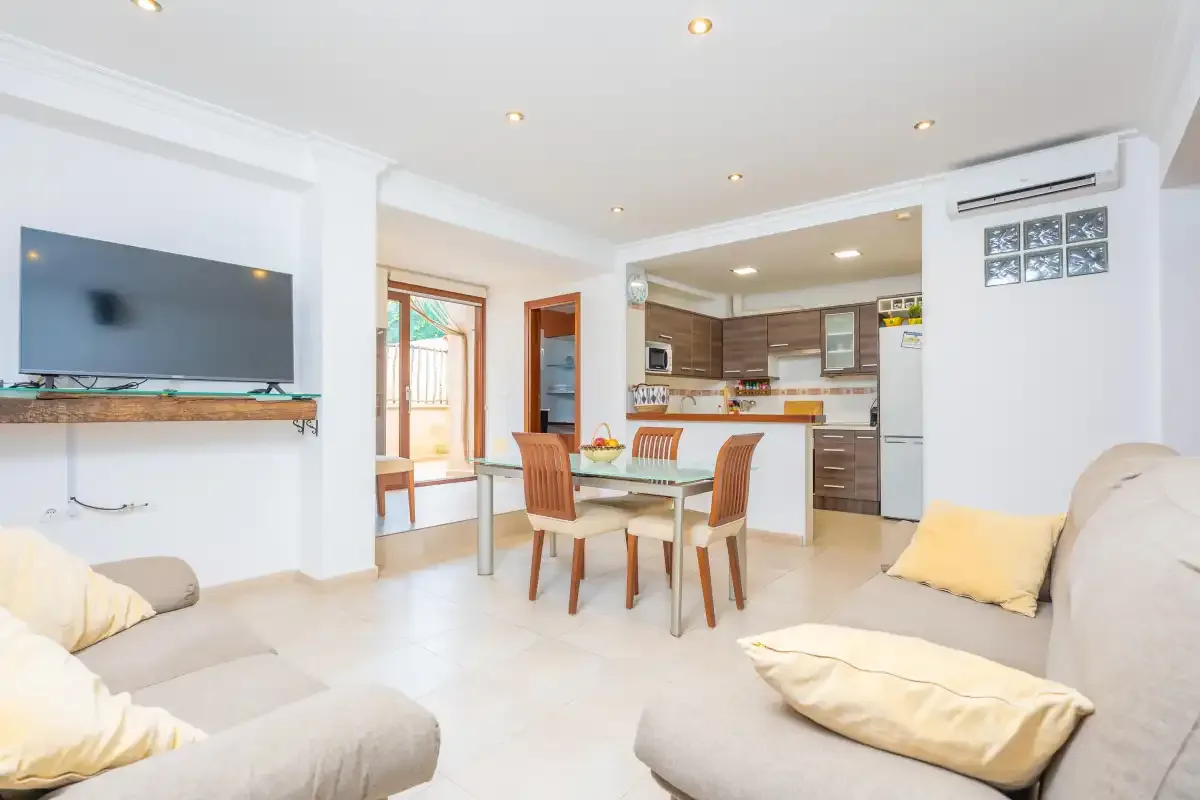Una luminosa zona abierta de estar y comedor con la cocina al fondo.