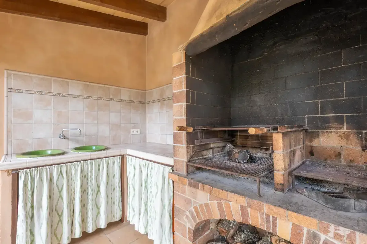 Un rincón de cocina rústica con una encimera de azulejos y una gran chimenea de ladrillo.