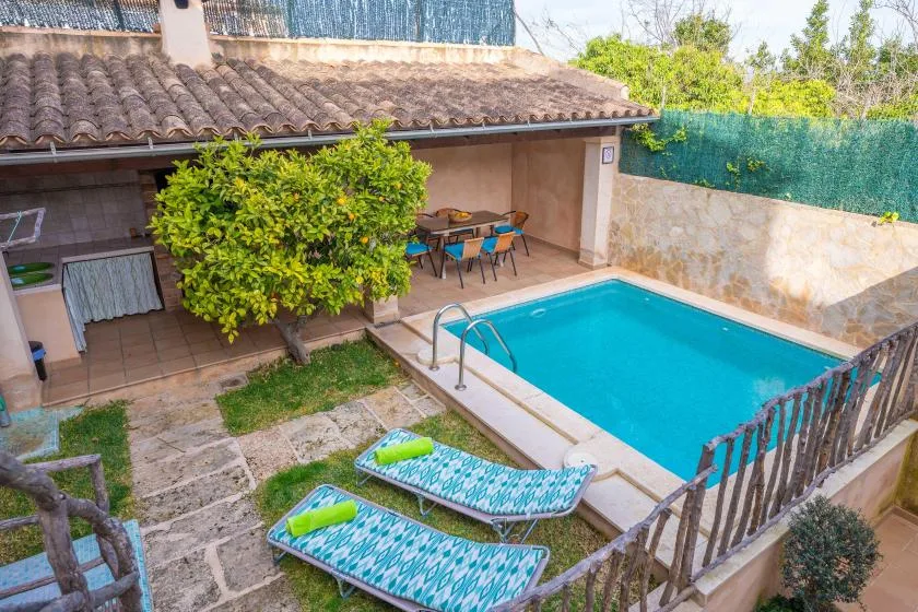 Una piscina en un patio junto a una terraza embaldosada con asientos al aire libre.
