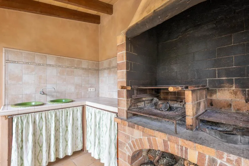 Una zona de cocina alicatada con encimera y una gran barbacoa de obra.