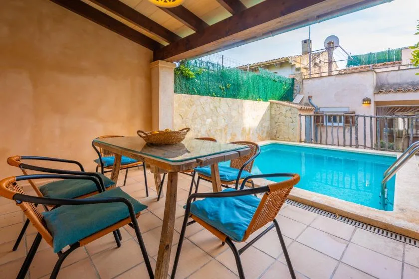A covered patio with seating overlooks a swimming pool.